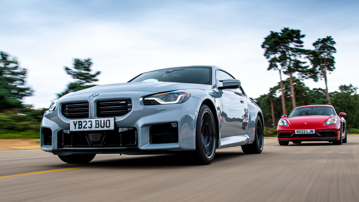 Close-up of the BMW M2 and Porsche 718 Cayman GTS rear ends, showcasing their distinct exhaust and taillight designs